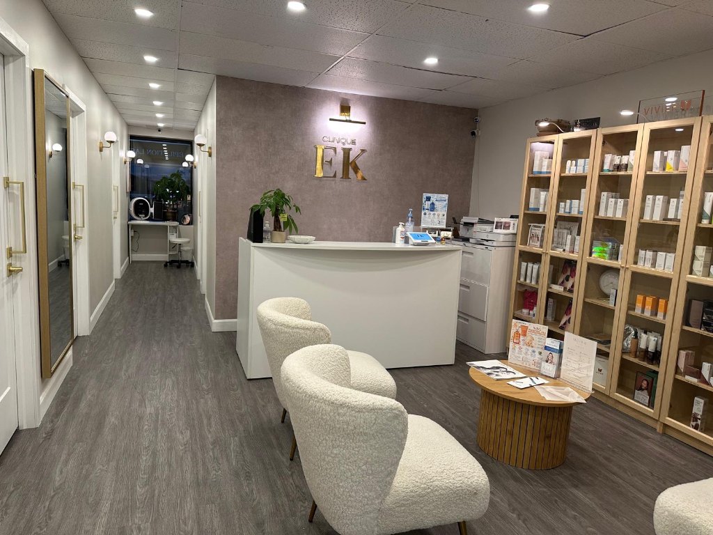 Réception de la Clinique EK avec son comptoir d’accueil, ses fauteuils blancs et ses étagères en bois